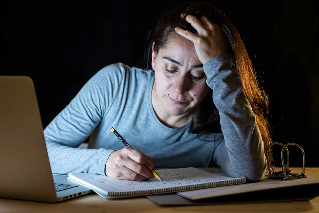 Joven estudiante de posgrado reflexionando mientras sostiene su laptop, representando la importancia de cuidar la salud mental en estudiantes de posgrado en un entorno académico demandante.