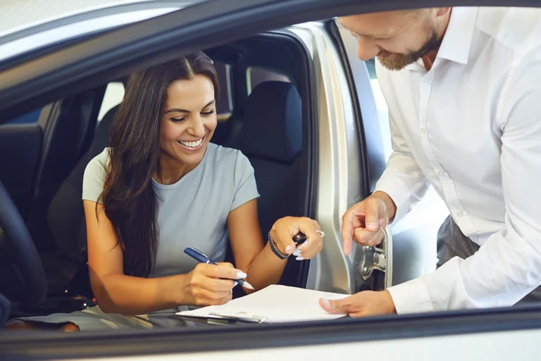 Joven mujer firmando la compra de su nuevo auto gracias a los créditos automotrices que otorgan estos bancos