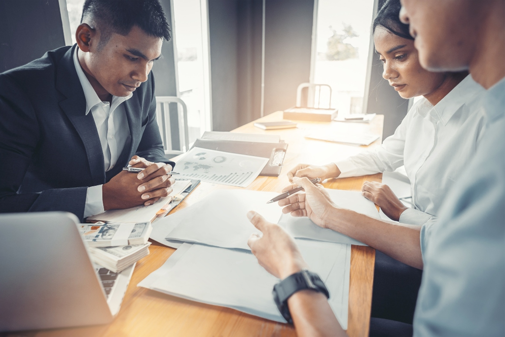 Jóvenes analizando sus documentos financieros para solicitar un crédito