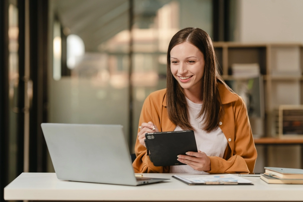 Estudiante revisando opciones de posgrados de psicología en una laptop, con libros y materiales de estudio alrededor.